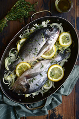 Raw fresh dorado prepared for baking with onion, lemon and thyme. Top view with copy space.