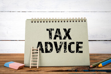 Tax Advice. Green notepad on wooden texture table and white background
