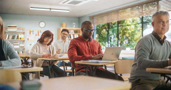 Adult Education Center: Diverse Mature Students Learning in Classroom, Using Laptops and Writing in Notebooks. Group of People Taking a Workshop on Improving Professional Work Skills