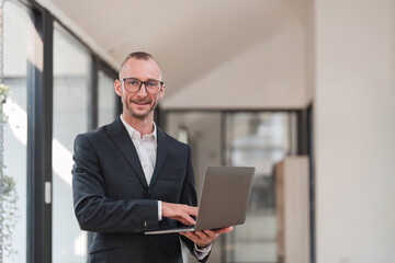 Successful businessman standing in modern office Use a laptop computer Organization or financial manager who is successful in planning investment projects