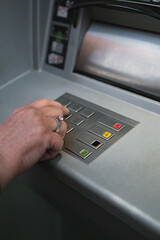 Middle-aged woman using ATM pressing the PIN security on the number pad.