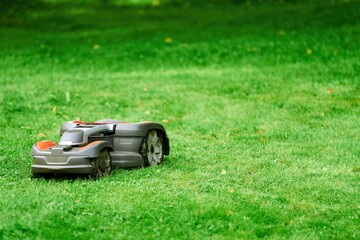 Robotic lawn mower on grass, side view. Close up isolated of automatic lawn mower. Smart lawn...