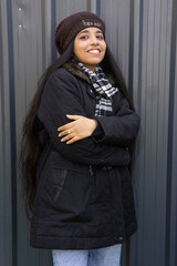 Young indian happy woman freezing, shivering wearing winter jacket with warm scarf and cap standing...