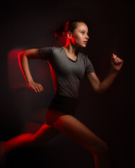 Teen girl athlete running against black background. Red motion blur is added purposefully.