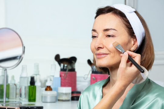 Beautician put makeup prime foundation cream on woman's face - Powered by Adobe