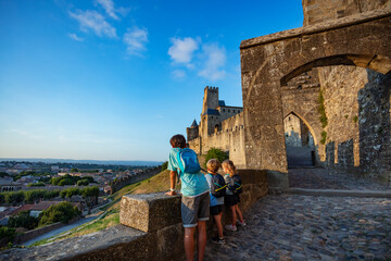 Joyful kids explore Carcassonne castle at sunset, enjoy panorama