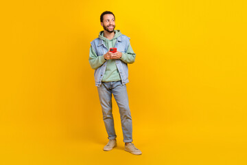 Fototapeta na wymiar Full body length photo of young latin guy boyfriend male hold phone thinking glovo delivery look mockup isolated on yellow color background