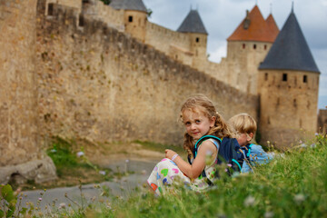 Children sightsee Carcassonne medieval site during vacation