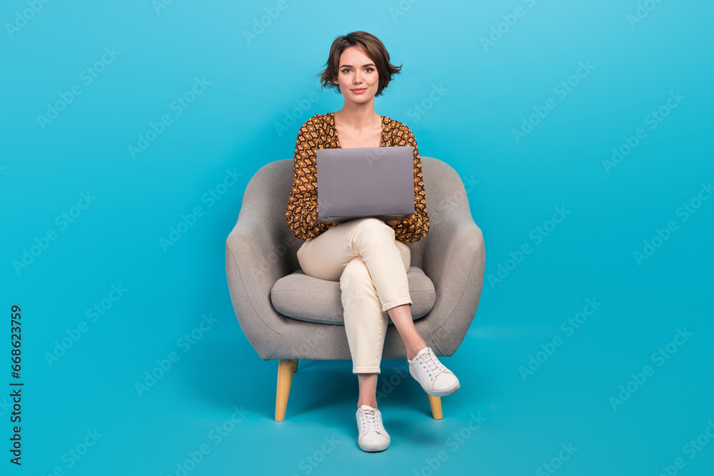 Poster full length portrait of gorgeous positive person sit soft chair use netbook isolated on blue color b