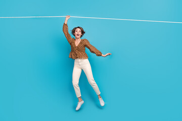 Photo of surprised lady hanging on rope playing incredible extreme sport game isolated blue color background - obrazy, fototapety, plakaty