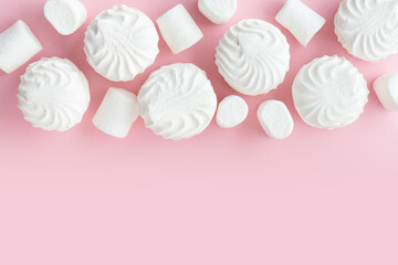 White marshmallows and zephyr on light pastel pink table. Banner with empty space for the text