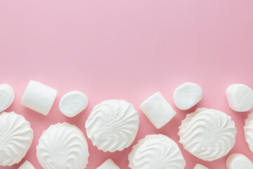 White marshmallows and zephyr on light pastel pink table. Banner with empty space for the text