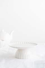 Empty tableware - white plate cakestand on white table as a background for a dessert