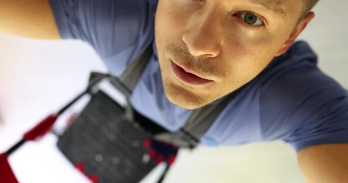 Electrician on stepladder works in new house on construction site. Portrait of master electrician replacing light bulb and repairing electrical and wires