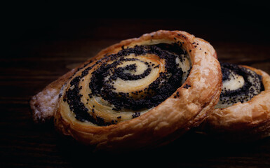 Two delicious buns with poppy seeds on a dark background.