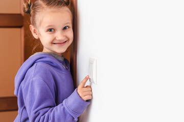 Turn off Light. Child Girl Switch off the Light to Save Energy. White Wall Background. Copy Space....
