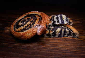 Two poppy seed buns whole and cut on a wooden background.