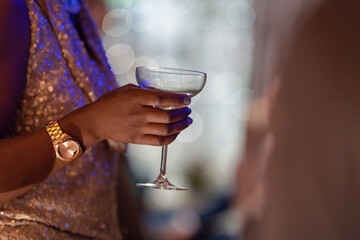 Female's Hand holding a drink near a wine rack