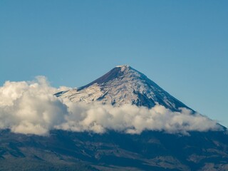 Majestic mountain peak surrounded by a picturesque landscape of fluffy white clouds.