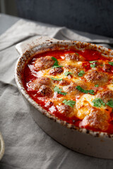 Meat balls in tomato sauce with mozzarella cheese and parmesan on table close up vertical photo