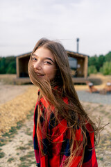 Fototapeta premium Close-up portrait of the face of a beautiful girl who runs to wooden cabin in woods and looks back