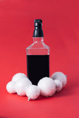 Christmas decorations glass of bottle and a white bauble with copy space against a red background....