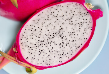 Delicious cut dragon fruit (pitahaya) on blue background, flat lay. 