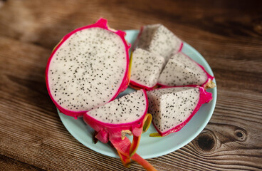 Red dragon fruit or pitahaya on plate on wooden background, Tropical fruit in summer season. 