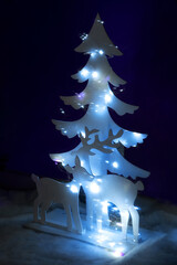 New Year's background with decorative Christmas tree and reindeer decorated with lights and purple...