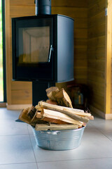 A pile of chopped firewood for lighting a fireplace lies in an iron bucket in country house