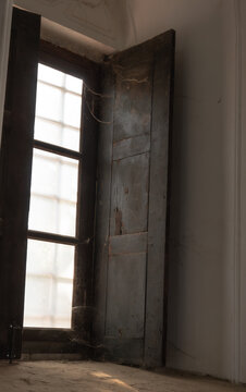 Sun rays coming in through the dark old window with sooty glass