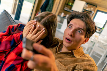 Young couple while watching a horror film The guy is surprised and girl covers her face with her...