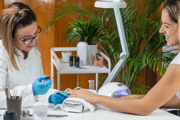 Nail manicure session at beauty salon. Expert technicians making beautiful, perfectly manicured nails