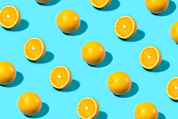 Trendy Summer food pattern made with oranges on bright light blue background. Whole and sliced oranges. Minimal summer concept.