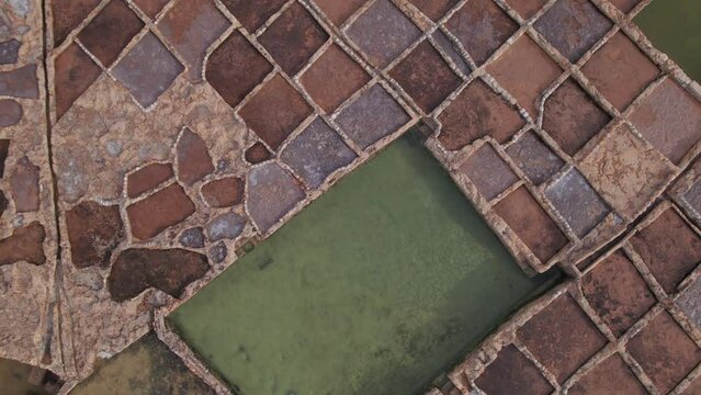 Aerial panoramic drone footage of Salt evaporation ponds (salterns) (salt pans) located near Qbajjar on the Maltese Island of Gozo, Malta