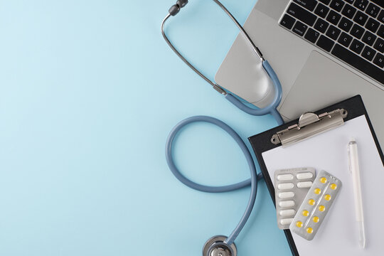 Embrace the convenience of virtual healthcare appointments. Top view photo of laptop, stethoscope, clipboard, pen, drugs on light blue background with promo zone