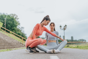 Naklejka na ściany i meble Athletes in an urban park engage in a fitness routine. Two fit females demonstrate their body transformation, performing cardio and stretching exercises with friends.