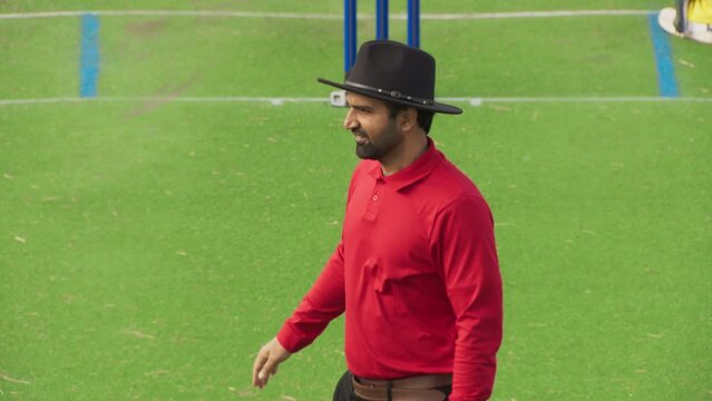 Portrait of an Official Cricket Umpire Watching a Match Between Two Teams. Judge Showing Boundary 4 Hand Sign, Enforcing Rules and Arbitrating the Play. Footage for Sports TV Broadcast Playback