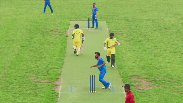 Two Yellow Team Batsmen Successfully Scoring Cricket Runs, While the Bowler Player Waiting for the Ball to Return From a Field Player. Professional Cricket Match TV Broadcast Footage