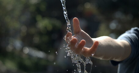 Close-up child hand in water fountain captured in high-speed 800 fps slow-motion. Refreshing liquid...