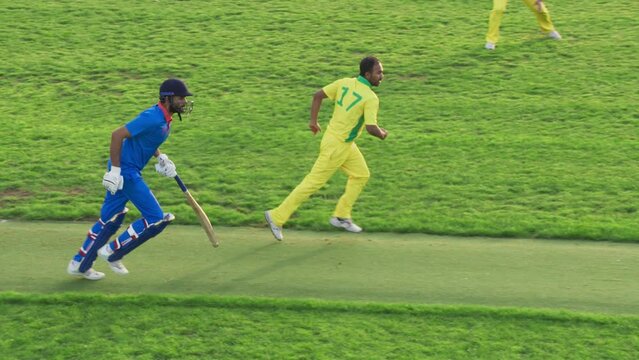 Portrait of a South Asian Cricket Player in Yellow and Green Uniform Throwing the Ball on a Pitch. Professional Indian Bowler is Aiming to Hit the Wicket. Sports TV Channel Broadcast