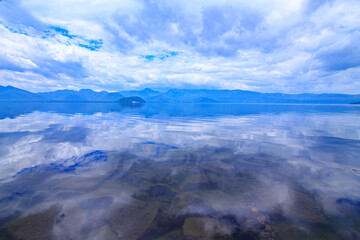北海道、屈斜路湖の雲に覆われた空を鏡の湖面に反射する風景。