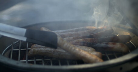 Cooking sausages in grill Barbecue captured with smoke, food preparation BBQ