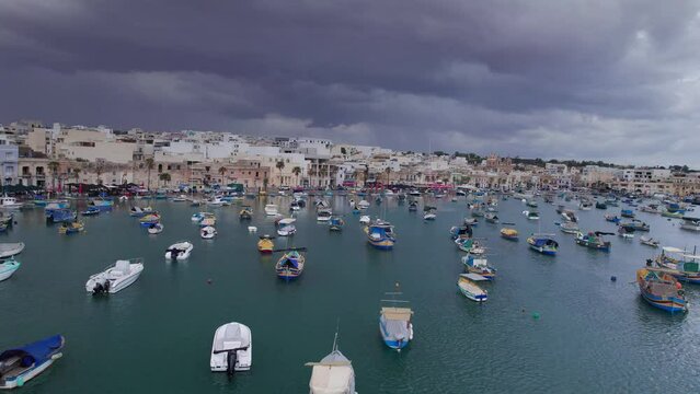 Aerial panoramic drone footage traditional eyed colorful boats (Luzzu) in the Harbor of Mediterranean fishing village, Marsaxlokk, Malta