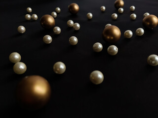 Scattered Plastic beads, white and golden on black background. Beads for jewelry making.