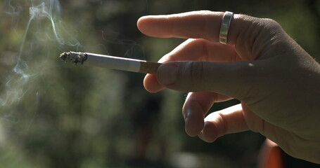 Finger tapping into cigarette ash falling off captured in. Close-up hand holding addictive substance