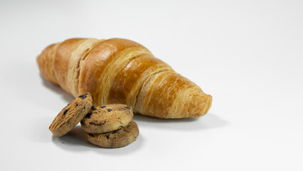 Chocolate chip cookies and croissants are placed in a wicker basket on a white cardboard background. Croissants on a white background. Chocolate chip cookies on a white background
