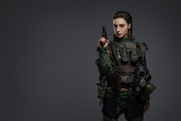Portrait of a female soldier in military uniform with a pistol, embodying a rebel or partisan in a Middle Eastern conflict against a gray backdrop