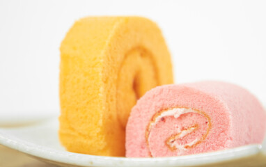 Orange roll cake and strawberry roll cake. Orange rose cake on a white crate background.