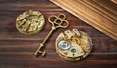 Old gold key and clockworks on wooden background. Escape room game banner.